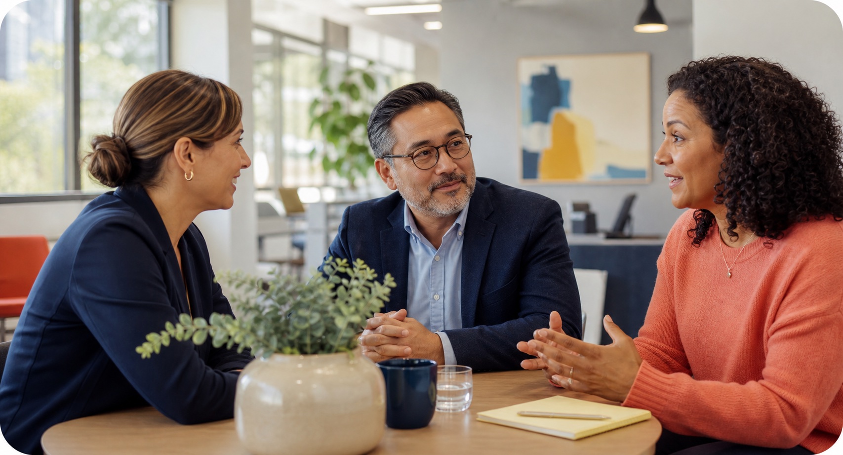 Three professionals having a relaxed conversation in a bright office